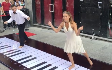 couple plays the pink panther theme on big piano